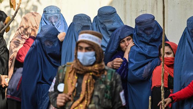 A Taliban fighter stands guard as women wait in a queue during a World Food Programme cash distribution in Kabul on November 29, 2021. Picture: AFP