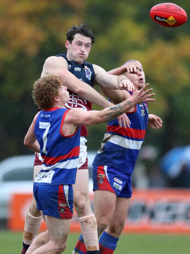 Sandhurst’s Connor Sexton comes over the top to spoil two Gisborne opponents. Pictures: Yuri Kouzmin