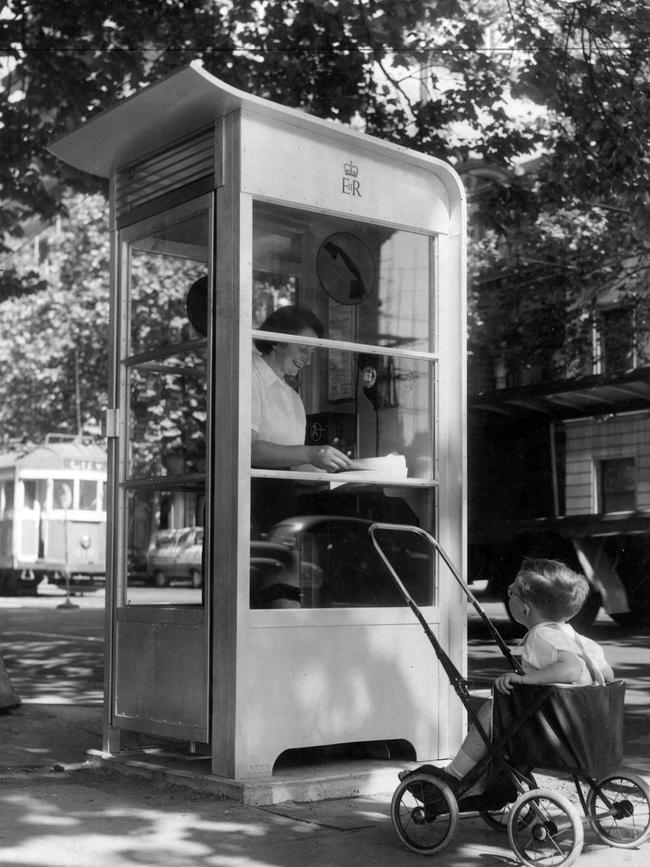 A boy waits while his mother makes a call from a telephone box at the corner of Spring and Collins streets in 1958.