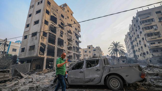 A man walks past cars and buildings destroyed in Israeli strikes in Gaza City on October 8, 2023. Picture: Mahmud Hams/AFP