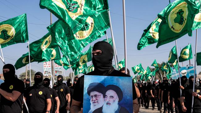 A member of the Imam Ali Battalions holds up a picture depicting Iran's late and current supreme leaders Ayatollah Ruhollah Khomeini, right, and Ali Khamenei, in Baghdad, Iraq, in early April. Picture: AFP