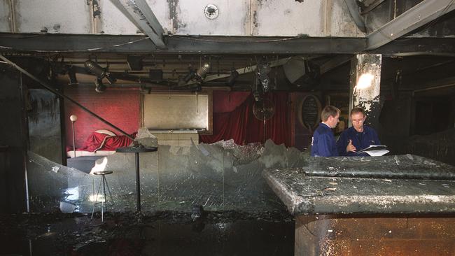 Fire investigators examine the burnt-out interior of Q Bar, including the shattered glass walls which surrounded the dancefloor, after it was destroyed by fire on March 6, 2001.