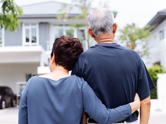 Happy senior couple from behind looking at front of house and car