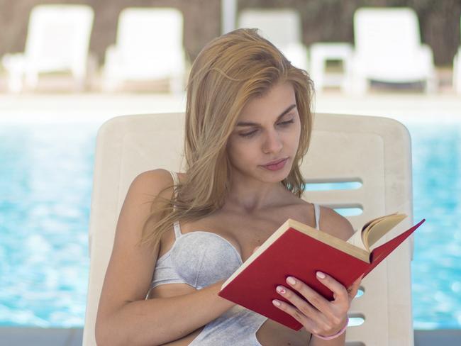 Woman reading book on sunlounger on vacation