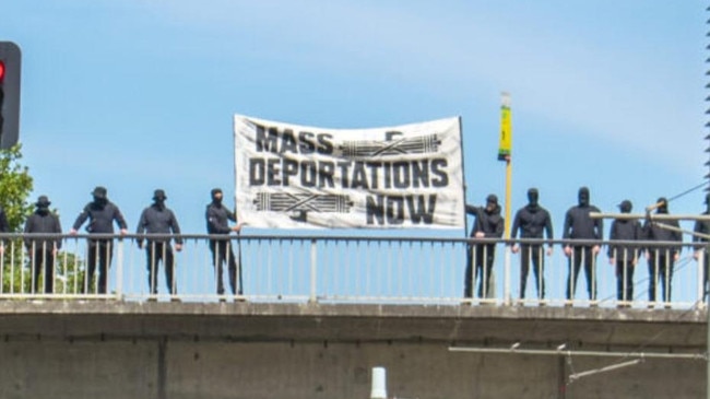 The group of masked protesters on the Morphett St bridge in Adelaide Picture: 7NEWS