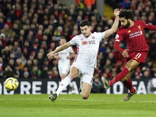 Sheffield United's David McGoldrick, left, tries to block a shot from Liverpool's Mohamed Salah during the English Premier League soccer match between Liverpool and Sheffield United at Anfield Stadium, Liverpool, England, Thursday, Jan. 2, 2020. (AP Photo/Jon Super)