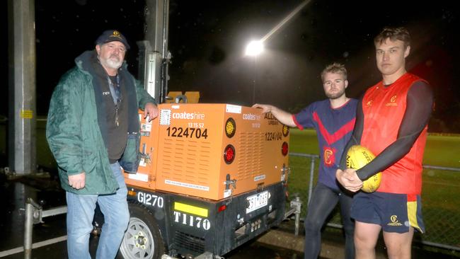 Flinders Park Football Club chairman John Cousins with frustrated players Jake Macro and Lachlan Fairly. The club has had to hire portable lights throughout this season after thieves have targeted copper from the oval’s light. Picture Dean Martin.