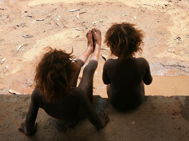 **FILE** An undated file image of sisters playing in the mud after a rare rain at Hoppy's 'town camp' on the outskirts of Alice Springs in the Northern Territory. Shocking claims of youth sexual abuse and prostitution involving indigenous children in far north Queensland communities have emerged in a government-commissioned report, Saturday, March 12, 2016. (AAP Image/Marianna Massey) NO ARCHIVING