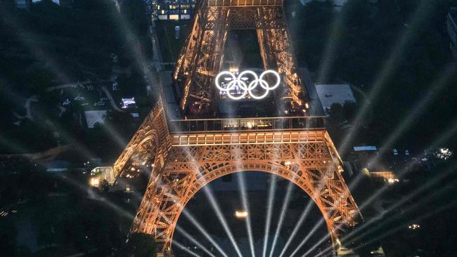 TOPSHOT - A photograph taken from an helicopter on July 26, 2024 shows an aerial view of the Eiffel Tower and the Olympics Rings lightened up during the opening ceremony of the Paris 2024 Olympic Games in Paris. (Photo by Lionel BONAVENTURE / POOL / AFP)