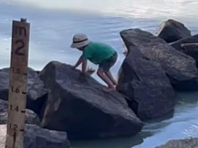 Shocking footage has emerged showing a young child playing dangerously close to multiple crocodiles at a crossing in the Northern Territory.