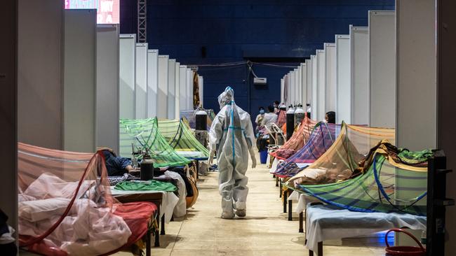 A medical worker in PPE observes patients infected by Covid-19 inside a makeshift care facility at the Commonwealth Games Village in New Delhi. Picture: Getty