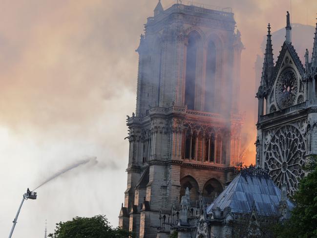 Firefighters douse flames rising from the roof at Notre-Dame Cathedral in Paris on April 15, 2019. - A fire broke out at the landmark Notre-Dame Cathedral in central Paris, potentially involving renovation works being carried out at the site, the fire service said. (Photo by Thomas SAMSON / AFP)
