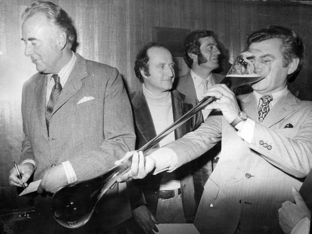 23/12/1974. Bob Hawke drinking a yard of ale at the official opening of the Bob Hawke Hotel. At left is Prime Minister Gough Whitlam.