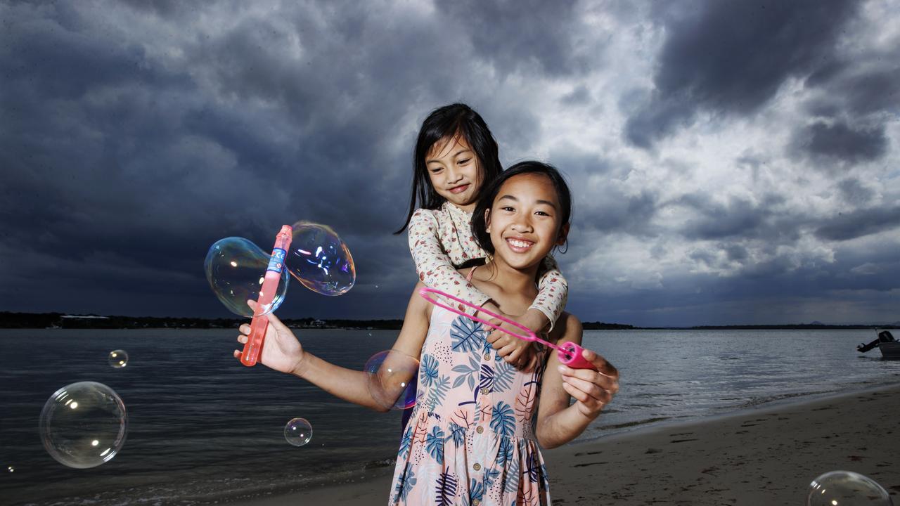 Sisters Renelle, 7, and Jaynelle Lacbayo, 10, from Oakey make the most of some holiday beach fun before the rain hits Bellara at Bribie Island on Tuesday. Picture: Lachie Millard