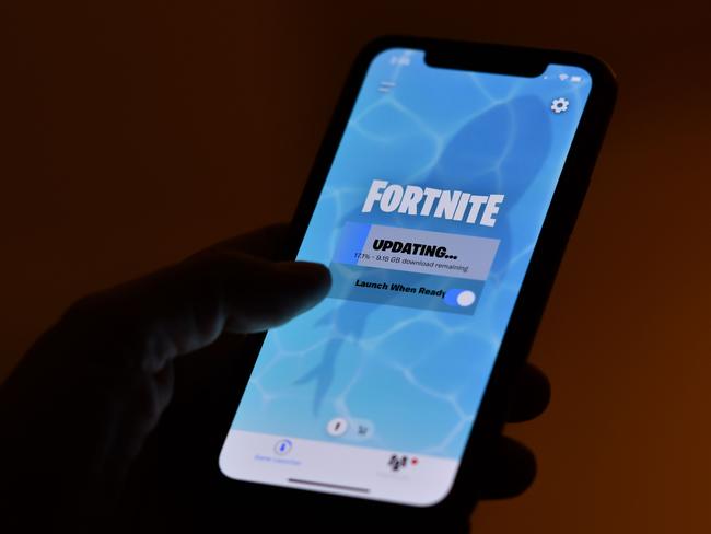 This illustration picture shows a person waiting for an update of Epic Games' Fortnite on their smartphone in Los Angeles on August 14, 2020. - Apple and Google on August 13, 2020 pulled video game sensation Fortnite from their mobile app shops after its maker Epic Games released an update that dodges revenue sharing with the tech giants. (Photo by Chris DELMAS / AFP)