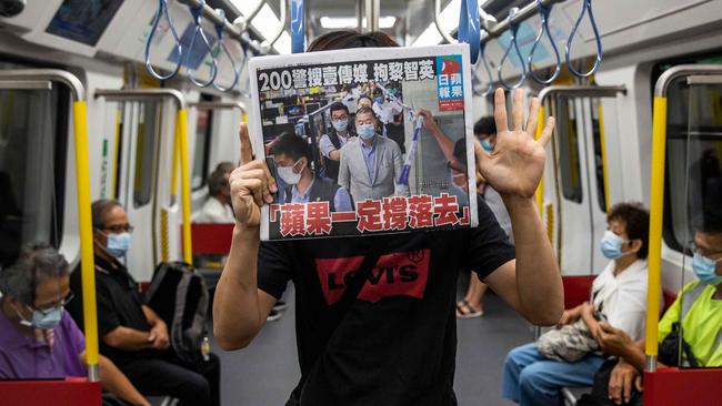 An activist holds a copy of the Apple Daily newspaper while raising his hand in a pro-democracy salute following the arrest in Hong Kong of Jimmy Lai. Picture: AFP