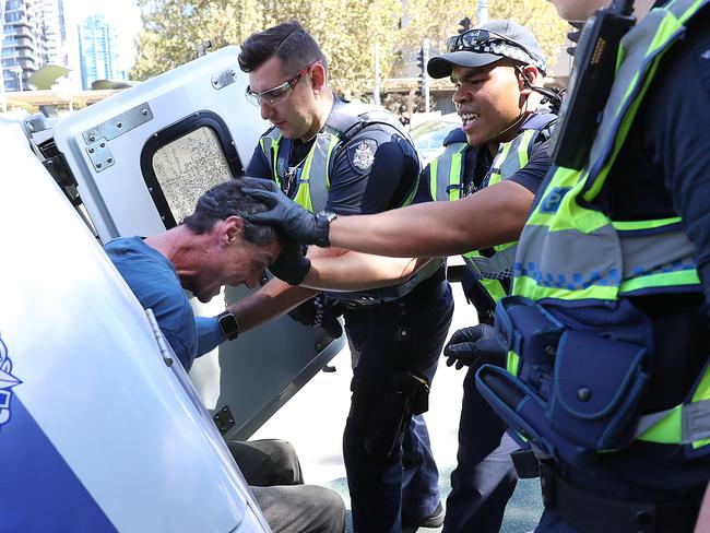 Officers force the man in to the back of a divvy-van after he continues to act violently. Picture: Alex Coppel.