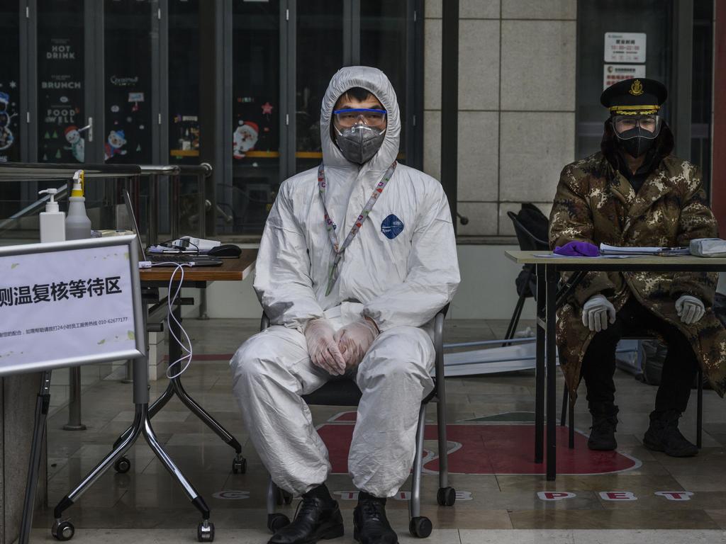 A man waits to check temperatures outside a residential building in Beijing. China. Picture: Kevin Frayer/Getty Images.