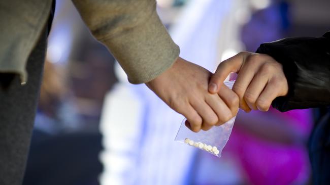 ecstasy being handed over at a house party. drug dealer istock