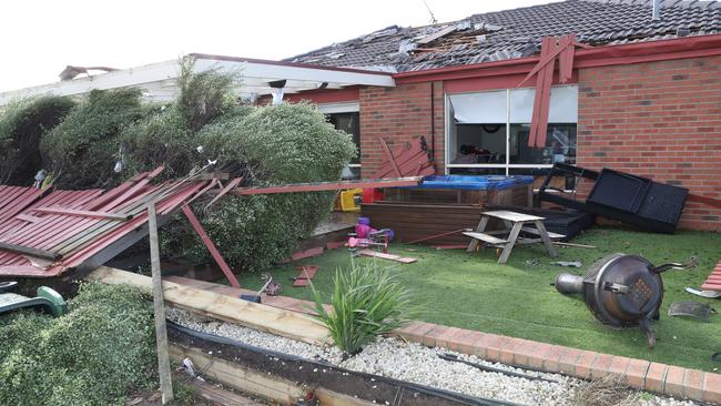 A damaged fence and roof at a home surrounded by debris. Picture: David Crosling