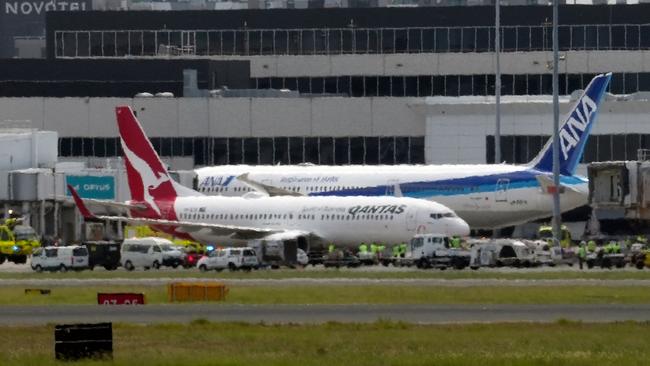 A Qantas Boeing 737 surrounded by emergency vehicles after losing an engine an hour before landing in Sydney. Picture: Andrew Leeson/AFP