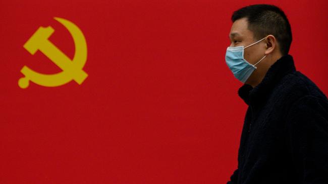 A man wearing a face mask as a preventive measure against the COVID-19 coronavirus walks past a Communist Party flag along a street in Wuhan in China's central Hubei province. Picture: Noel Celis/AFP