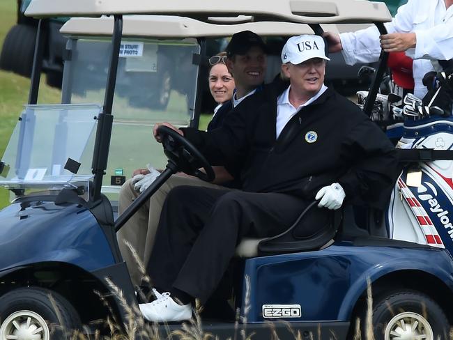 US President Donald Trump sits in a golf cart as he plays a round of golf at Trump Turnberry, his luxury golf resort, as people protest his UK visit nearby. Picture: AFP