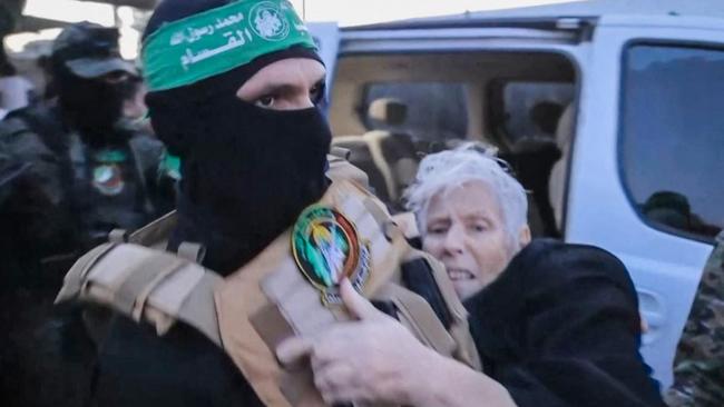 A member of Hamas' Al-Qassam Brigades carries a hostage over to officials from the International Committee of the Red Cross in Gaza, ahead of her transfer to Israel. Picture: AFP PHOTO / HO / HAMAS MEDIA OFFICE