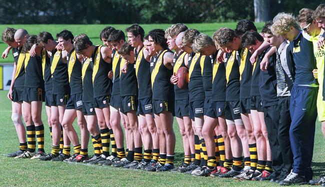 Glenelg under-17 footballers observe a minute's silence in memory of Chris Buss during a match at Elizabeth after his death in July, 2003.