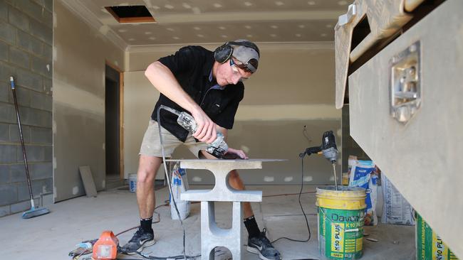 Fourth-year apprentice tiler for Bridgewater Homes Dale Harris-Smith cuts some bathroom tiles for a new house being built in the Cherrybrook Estate in Bentley Park. Picture: Brendan Radke