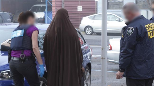 Police officers arrest a woman charged with being a member of Islamic State. Picture: AFP