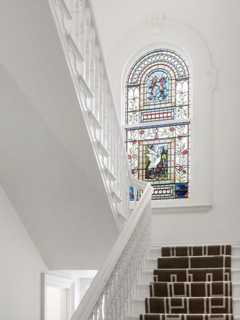 The soaring staircase window, once dulled by time, now floods the hall with light, showcasing colourful stained glass birds and vines.