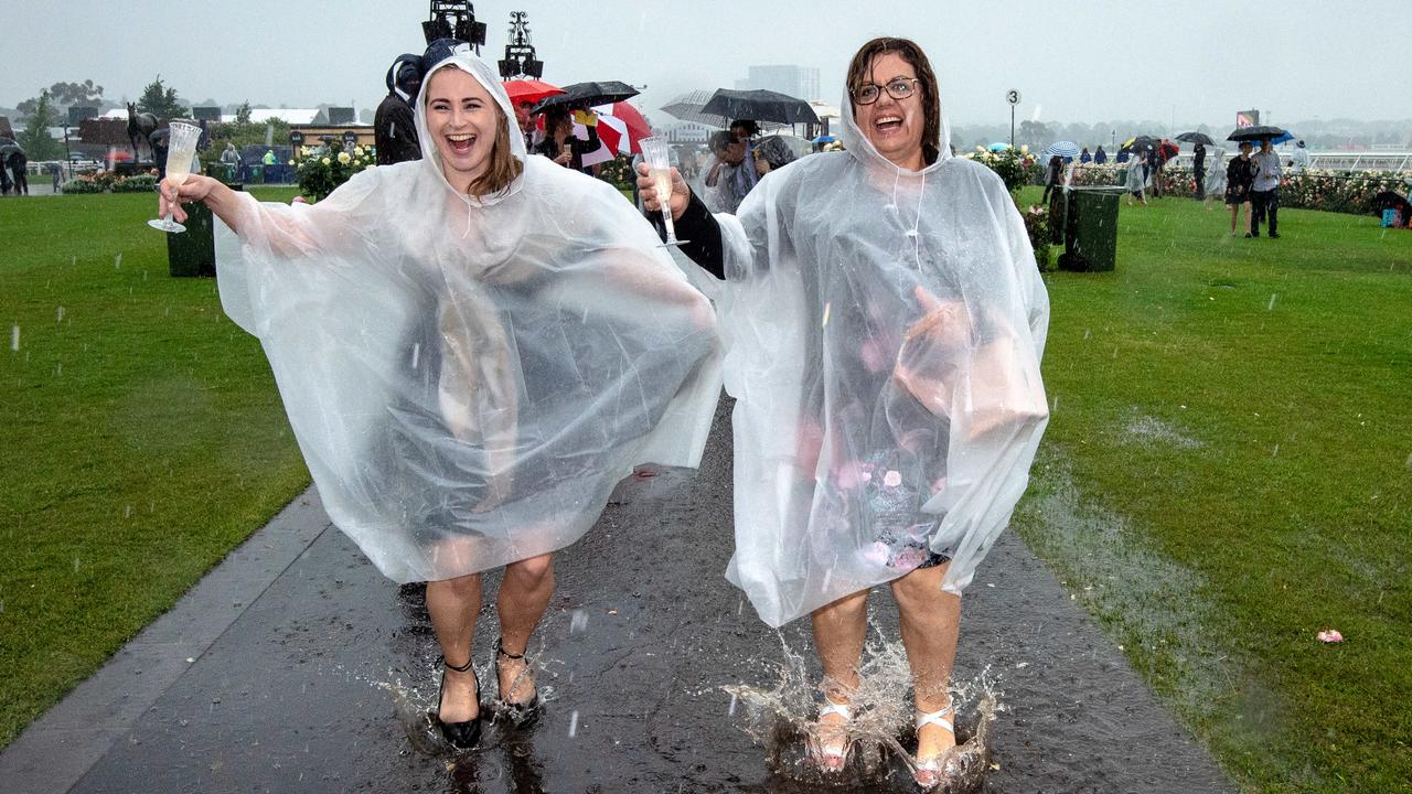 Soaked through. Trackside revellers dance in the rain at Flemington. Picture: Jason Edwards