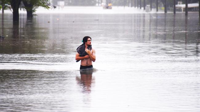 A man walks through floodwater on Miles Street in Ingham. Picture: Cameron Bates