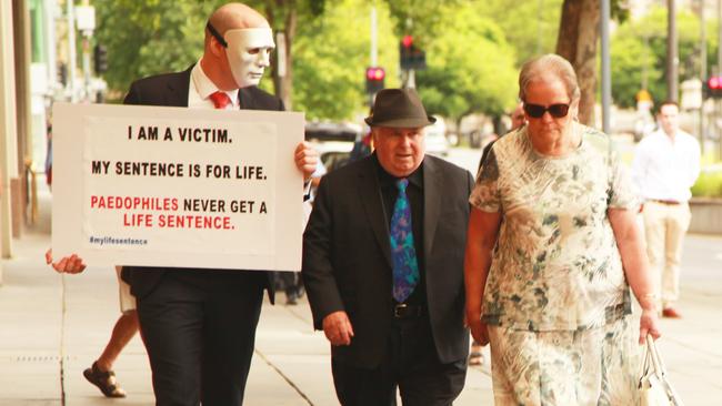 Vivian Frederick Deboo, centre, and his wife Margaret, right, are confronted by one of his victims "B", as he enters the District Court to face sentencing submissions on November 1.