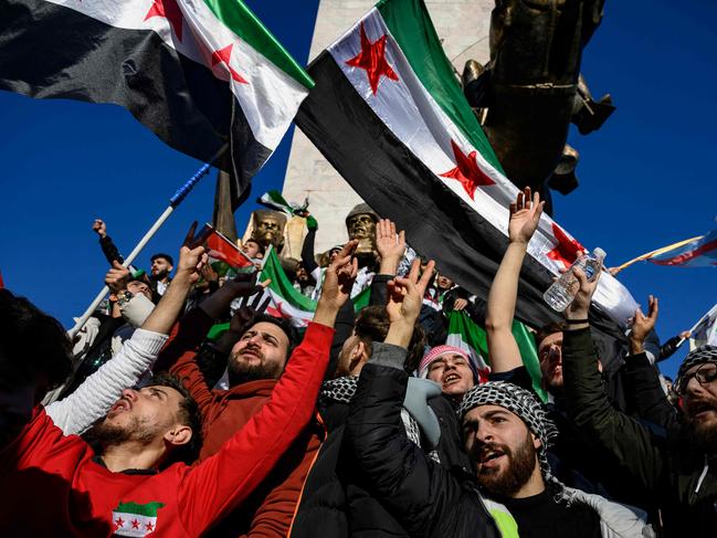 TOPSHOT - Syrian residents in Turkey wave Syrian opposition flags as they celebrate the fall of long-time ruler Bashar al-Assad after rebel fighters took control of the Syrian capital Damascus overnight, in Istanbul on December 8, 2024. Turkey's foreign minister said on December 8, 2024 the country wanted to help "guarantee security" in Syria after the fall of president Bashar al-Assad in the face of an offensive by Islamist-led rebels. (Photo by Yasin AKGUL / AFP)