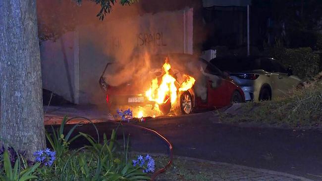 A car is set alight near anti-Semitic graffiti on Magney Street in Woollahra, Sydney, on December 11.