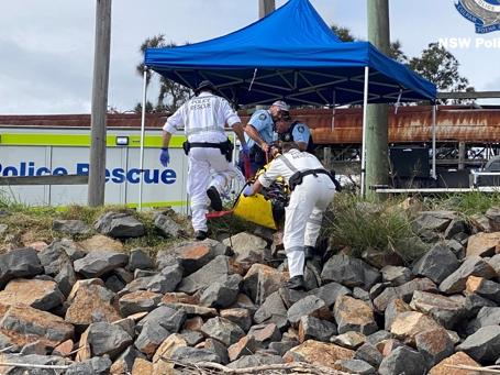 Police remove the man’s body from the short near the Port of Newcastle.