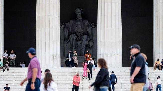 Tourists, some in face masks while others are not, visit the Lincoln Memorial in Washington. Picture: AFP.