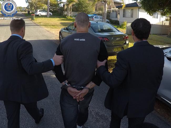 The man is led away by detectives following his arrest at Tanilba Bay today. Picture: NSW Police