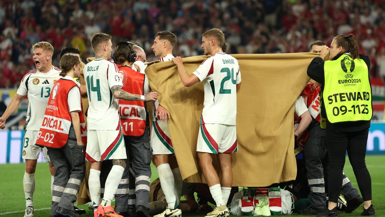 Players of Hungary hold up blankets as they assist medical staff by covering Barnabas Varga of Hungary (obscured) as he receives medical treatment.