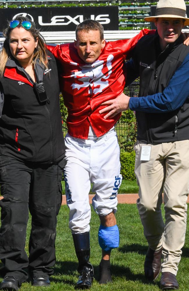 Damien Oliver is helped back into the jockeys’ room after the starting gates incident.