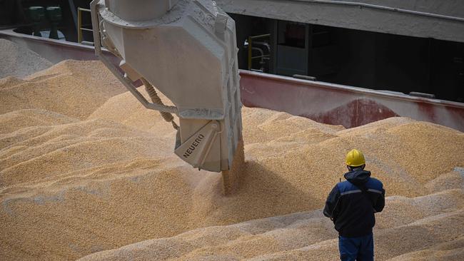 An operator remotely controls a corn loader on a ship.