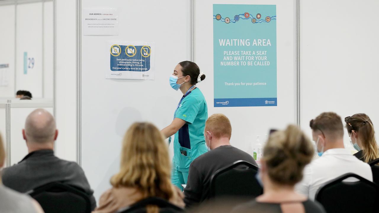 A staff member walks past a sign at a Covid-19 vaccination hub on the Gold Coast. Picture: NCA NewsWire /Jono Searle