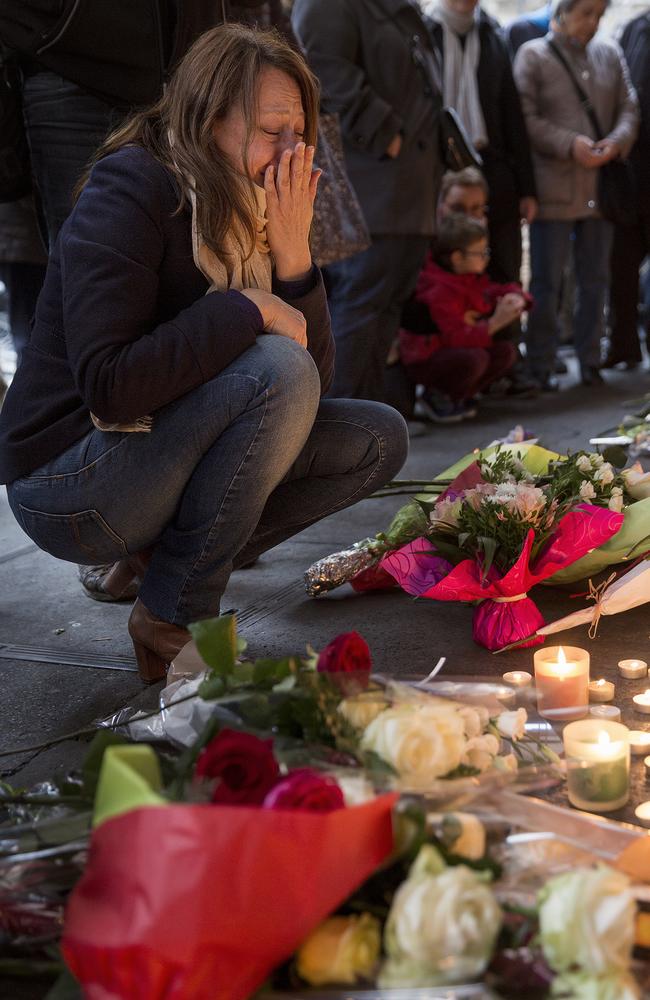 Emotional scenes ... a woman pays her respects at a floral memorial in front of La Belle Equipe cafe. Picture: Ella Pellegrini