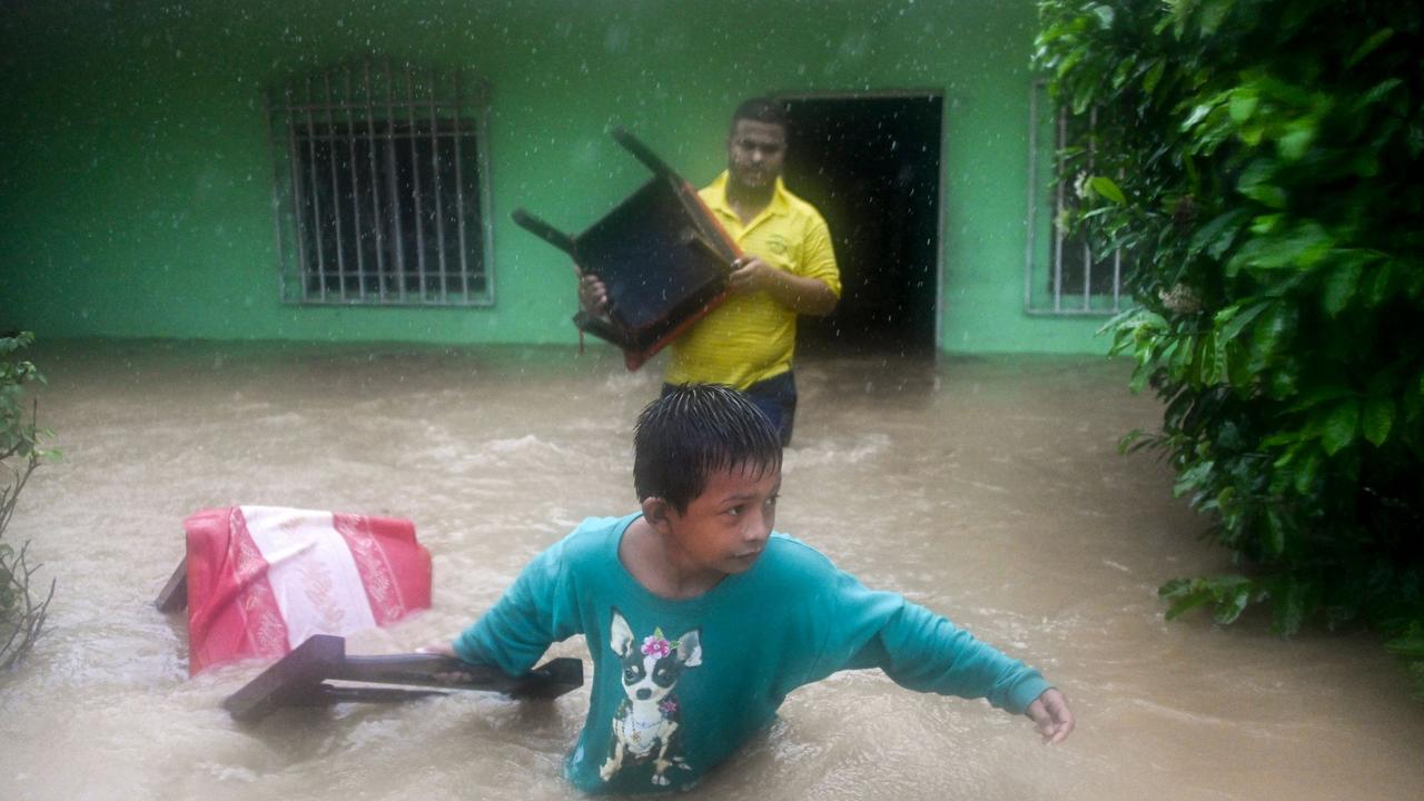 A boy and a man save chairs from a flooded house due to the heavy rains caused by Hurricane Eta in Puerto Barrios. Picture: Johan Ordonez/AFP