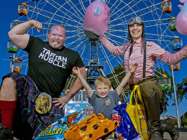 Strong Man Jordan Biggie Steffans  holds Walker a 10 week old Shih Tzu puppy,Sonny Roux,4, with show bags and the amazing Captain Sky Doodles and his fairy floss creations all ready for the Adelaide Royal Show ticket sales being available.Wednesday,July,31,2024.Picture Mark Brake