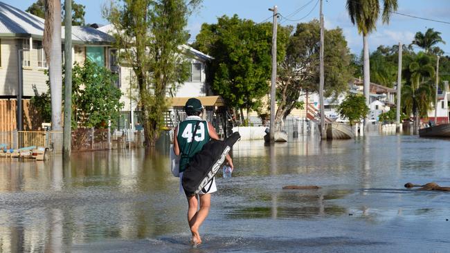 A residents carries takeaway food through flood waters on East St, Depot Hill.