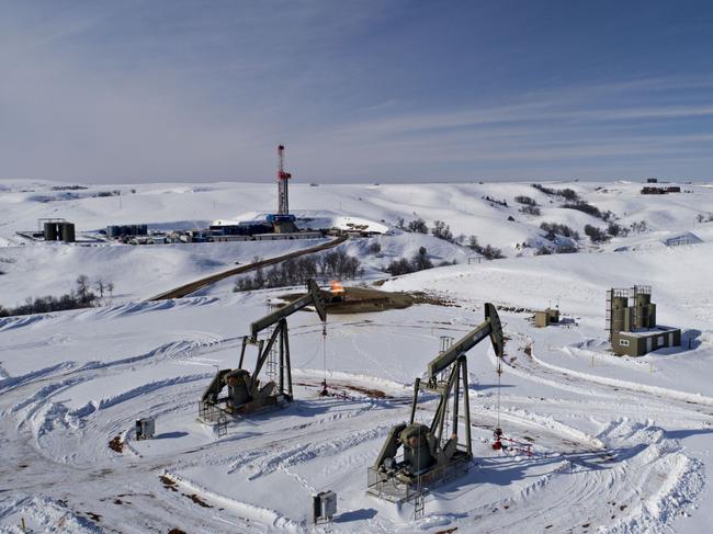 Pumpjacks operate as a drill rig sits on a well pad in the Bakken Formation in Williston, North Dakota, U.S., on Thursday, March 8, 2018. When oil sold for $100 a barrel, many oil towns dotting the nation's shale basins grew faster than its infrastructure and services could handle. Since 2015, as oil prices floundered, Williston has added new roads, including a truck route around the city, two new fire stations, expanded the landfill, opened a new waste water treatment plant and started work on an airport relocation and expansion project. Photographer: Daniel Acker/Bloomberg