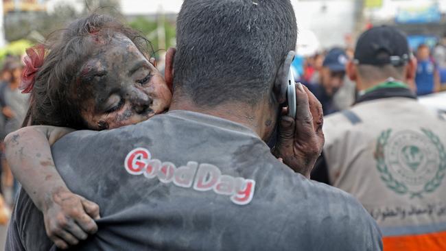 A Palestinian man covered with dust carries an injured baby girl into the Al-Shifa hopsital in Gaza City following Israeli strikes on October 29, 2023. Israel says Hamas has placed a major military headquarters underneath the hospital. Picture: Dawood Nemer / AFP